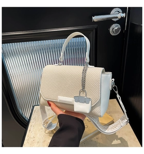 Detail of off-white woven square handbag with wide embroidered strap and mini bag charm