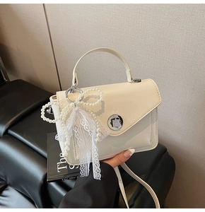 Détail du sac en cuir huilé blanc avec breloque nœud en perles et fermoir rotatif en métal