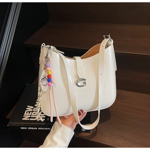 Detail of white leather hobo bag with silver G-buckle and colorful beaded charm