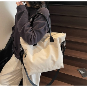 Détail du sac fourre-tout en toile blanche avec anses en cuir noir sur un escalier