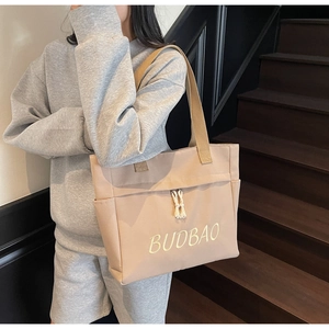 Detailed shot of beige canvas tote bag with BUDBAO embroidery and side pocket feature