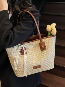Grand sac cabas en paille tressée beige avec poignées en cuir marron et nœud en dentelle
