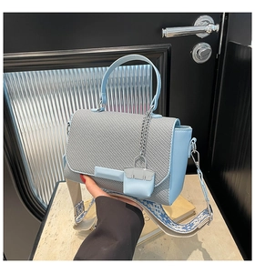 Detail of blue leather handbag with woven grey flap and stylish wave pattern wide strap