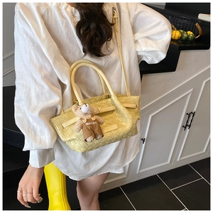 Detail of yellow woven bucket bag with adjustable strap and cute bear charm pendant