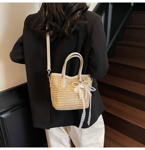 Detailed view of straw bucket bag with white lace bow and elegant pearl charms
