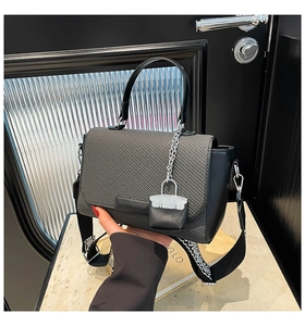 Gray woven handbag detail with silver lock charm and black geometric embroidery strap