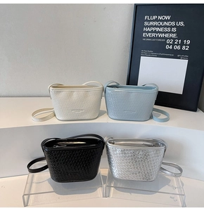 Détail des sacs seau à texture tressée en blanc, bleu, noir et finitions argent