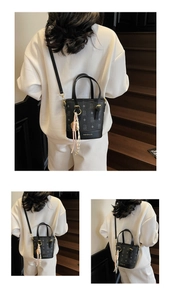 Detailed view of black bucket bag featuring geometric texture and elegant silk scarf accessory