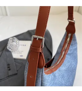 Détail d'un sac en jean avec bandoulière réglable en cuir marron et boucle argentée