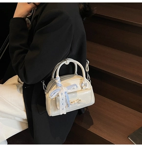 Detail of cream white Boston bag with blue checkered ribbon and white lace charm