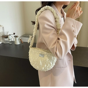 Detail of a beige pleated cloud bag with textured bubble fabric and silver metal plaque