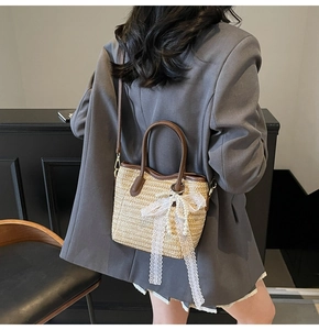 Detail of straw bucket bag with brown leather trim and white lace pearl bow charm