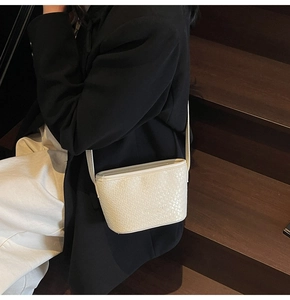 Détail de la texture tressée blanche d'un sac seau minimaliste avec fine bandoulière