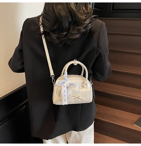 Mini cream leather Boston bag with bow and blue plaid ribbon shown as a crossbody bag