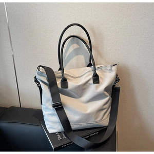 Détail d'un sac cabas en toile grise avec poignées noires et bandoulière réglable