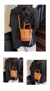 Detail view of a brown monogram bucket bag with tassel charm and adjustable strap