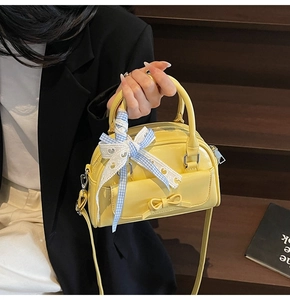 Detail of a bright yellow Boston handbag with a blue checkered ribbon and bow accent