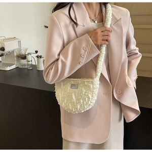 Detail of white textured ruched shoulder bag with metallic logo and wide pleated strap