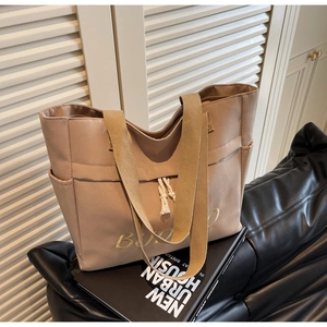 Detailed shot of khaki canvas tote bag featuring golden embroidery and white drawstring