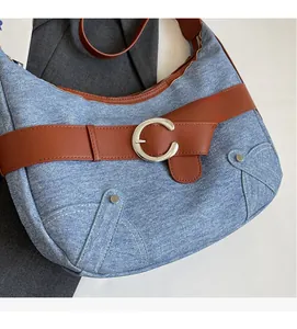 Détail du sac croissant en denim rétro avec lanière en cuir marron et boucle en C argent