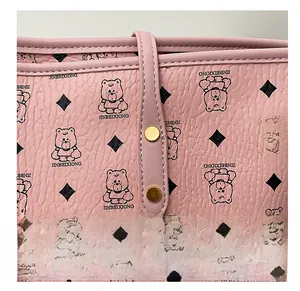 Detail of pink pebbled leather tote bag with classic bear print and gold rivet hardware