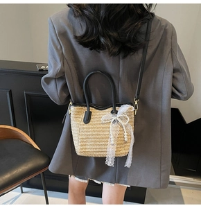 Detail view of woven straw bucket bag with black handles and elegant lace bow accessory