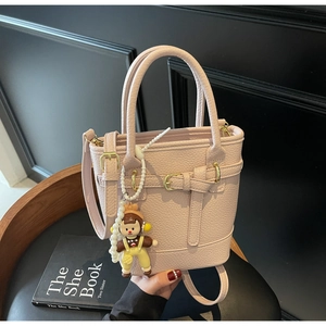 Detailed macro view of pink lychee grain leather bucket bag with cute cartoon charm