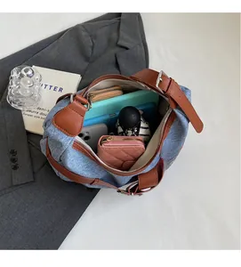 Vue détaillée de l'intérieur spacieux du sac à bandoulière en denim bleu et cuir marron