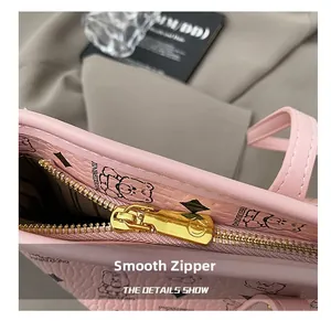 Detail of smooth gold zipper and printed bear logo on pink faux leather tote bag