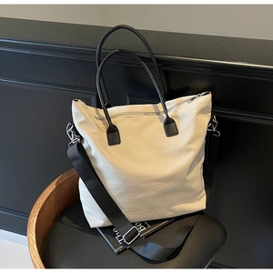 Détail du sac fourre-tout en toile blanc cassé avec poignées en cuir noir et fermeture éclair
