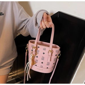 Pink bucket bag with cartoon bear pattern and adjustable strap shown by hand