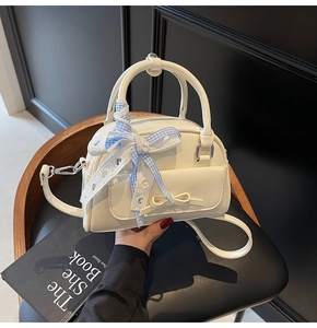 Detail view of cream Boston bag with checkered bow and silver hardware accents
