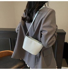 Détail de la texture tressée et bandoulière du sac seau bleu clair porté par un mannequin
