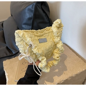 Detail of light yellow ruched cloud bag showing bubble texture and silver metal plaque