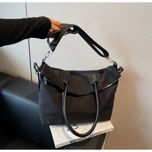 Détail du sac cabas en nylon noir avec poignées en cuir et bandoulière réglable