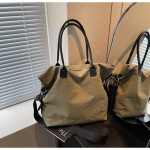 Gros plan du sac cabas en toile vert olive avec anses en cuir et bandoulière en nylon