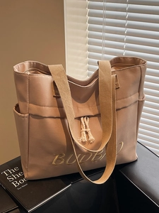 Minimalist beige canvas tote bag with embroidery on sofa under warm sunlight