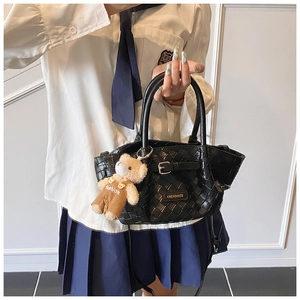 Close-up of black woven handbag with Cherimate logo and brown plush bear charm detail