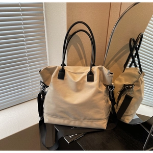 Détails du sac cabas en toile beige avec anses en cuir noir et bandoulière réglable
