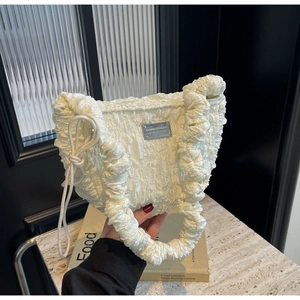 Close-up of white pleated cloud bag showing bubble texture fabric and silver metal plaque