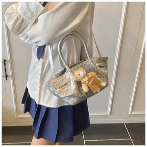 Detail of silver woven texture tote bag with a cute plush bear pendant accessory