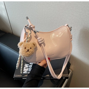 Close-up of pink patent leather shoulder bag with a cute brown teddy bear charm