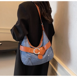 Détail du sac hobo en denim bleu avec bandoulière en cuir brun et boucle en C argentée