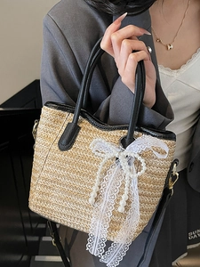 Contrast straw bucket bag with black leather handles and delicate pearl lace bow details