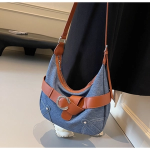Vue latérale d'un sac cabas en denim bleu et cuir marron porté par un mannequin en studio
