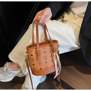 Close-up of brown leather bucket bag with bear patterns, tassel charm, and logo detail