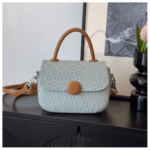 Detail of mint green crossbody bag with square embossed texture and round brown button