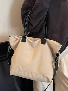Grand sac cabas en nylon beige avec poignées noires et bandoulière porté par un mannequin
