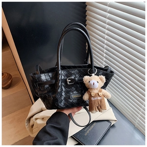 Detailed close-up of black woven texture tote bag with metal logo and bear charm
