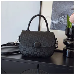 Detail of black checkered embossed handbag with round buckle and silver hardware accents